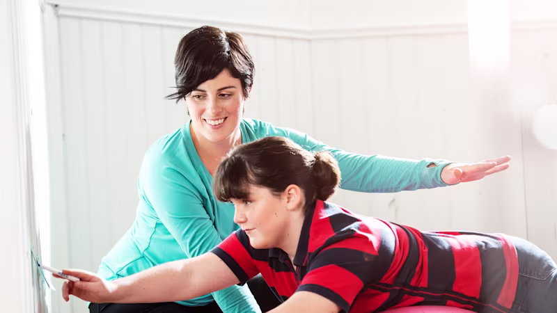 A Dynion user helps another on an exercise ball