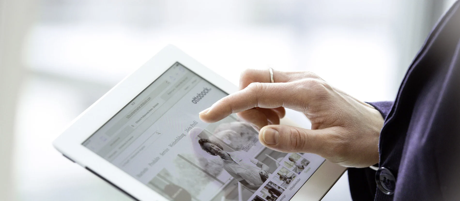 Eine Frau hält ein Tablet in der Hand mit der Ottobock Website auf dem Screen.