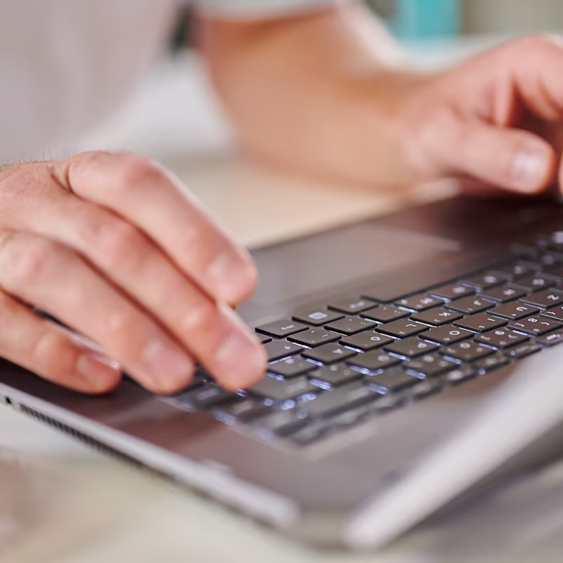 A Prosthetic Reimbursement Specialist on their laptop