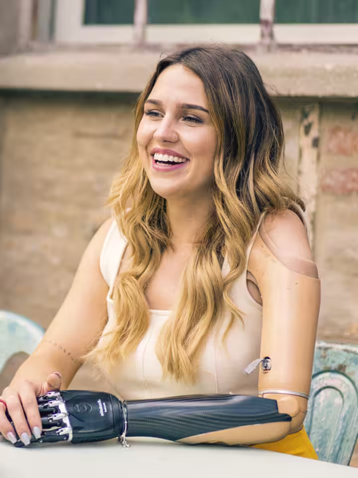 Eine Frau mit einer Armprothese unterhält sich mit einer anderen Frau. Sie trägt das Myo Plus von Ottobock.