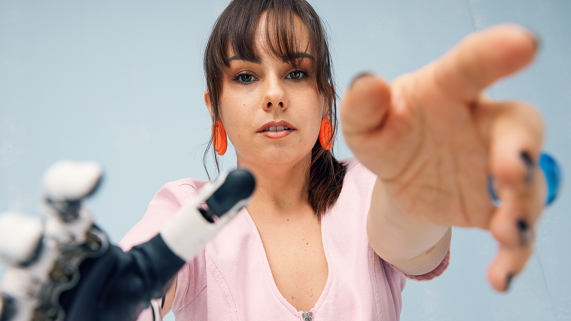 A close up shot of Ottobock ambassador Kiersten while she frames the camera with her artificial and biological hand.