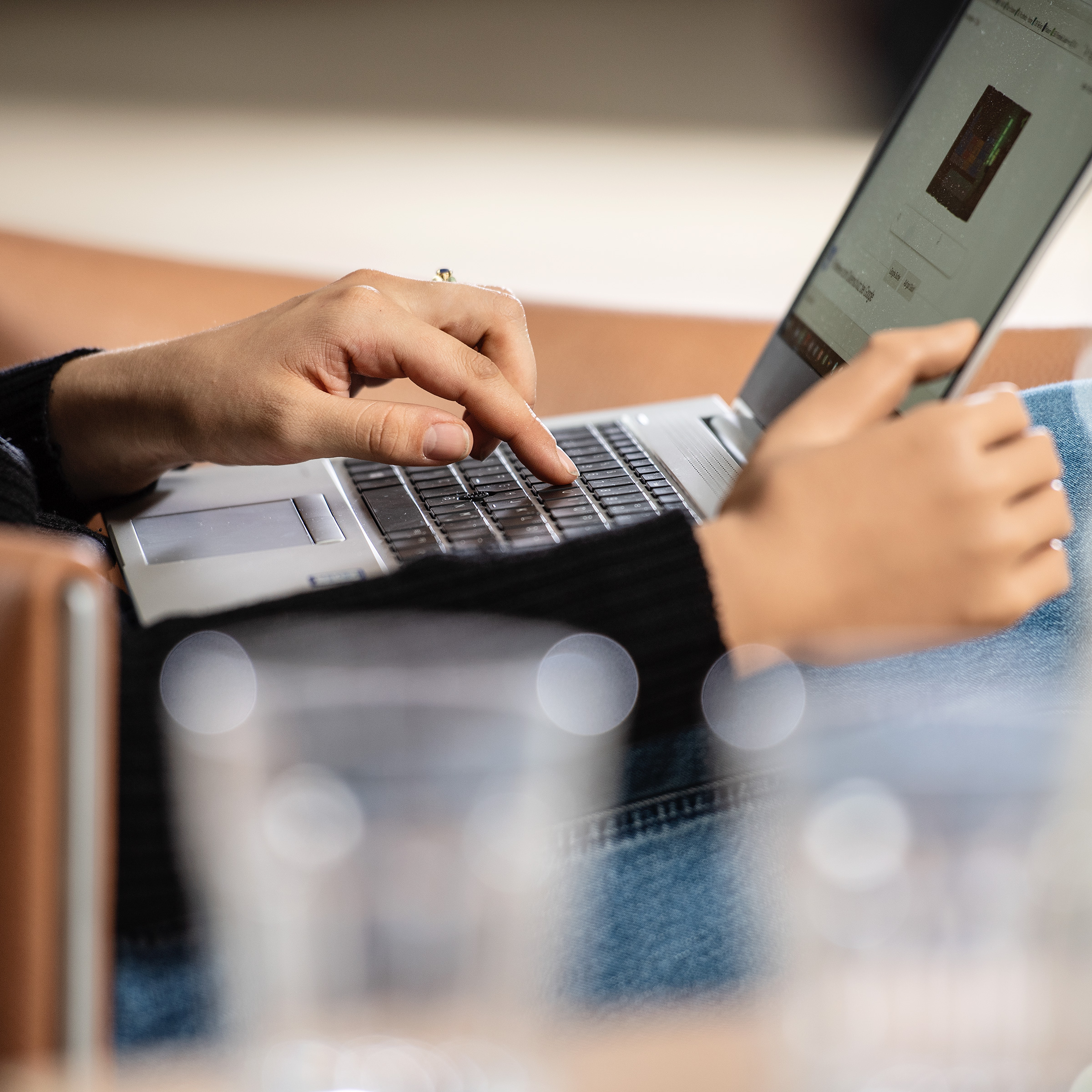 Ottobock prosthetic hand user seated with laptop, focus on her hands while working.
