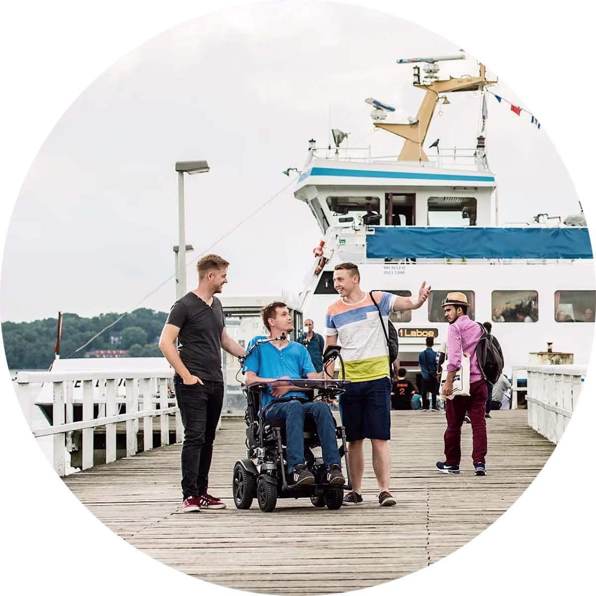 Man sieht einen Mann und zwei weitere männliche Personen rechts und links von ihm auf einer Seebrücke.