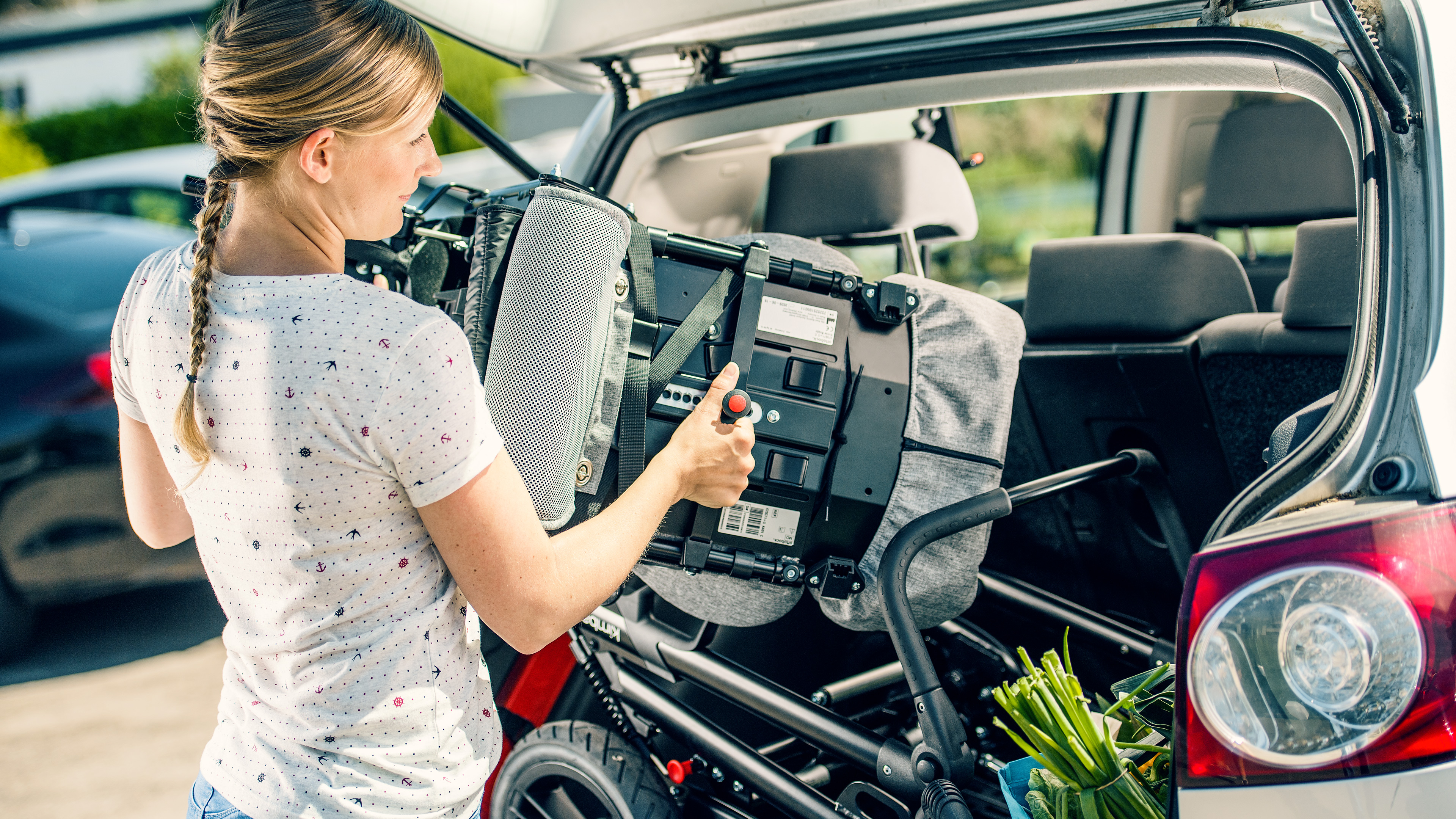 Mira's mother packs the Kimba buggy into the trunk of the car