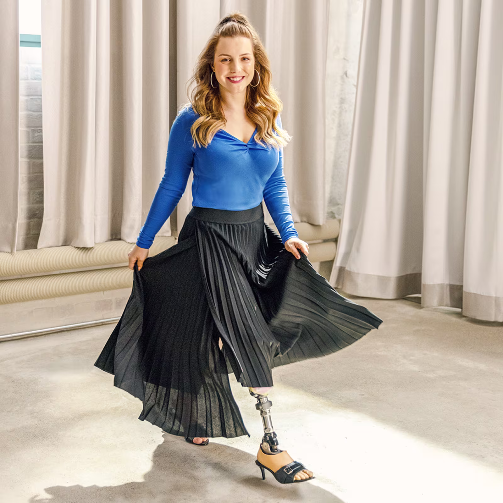 Eine junge Frau läuft durch einen hellen Raum und lächelt in die Kamera. Sie trägt den Taleo Adjust Prothesenfuß von Ottobock.