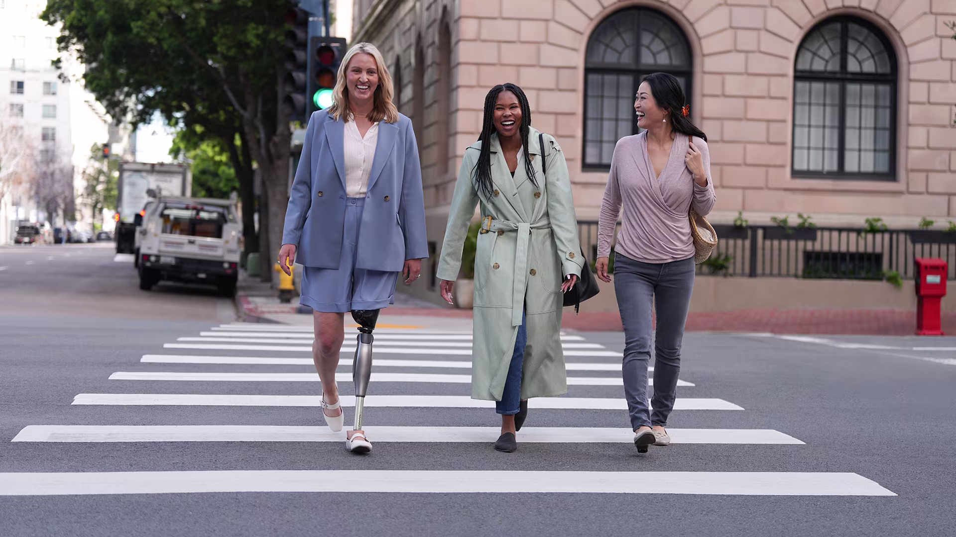 Three women crossing the street, one wearing a microprocessor-controlled knee