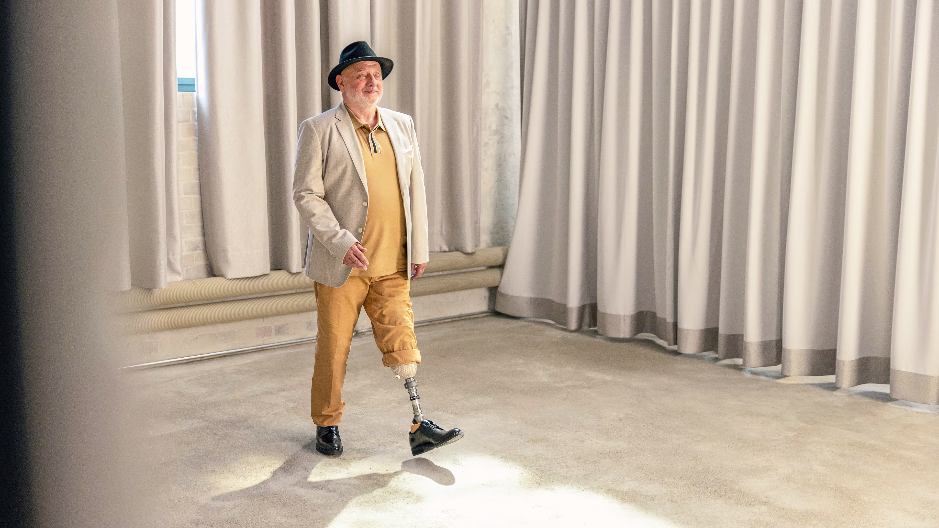 Ein unterschenkelamputierter Mann läuft durch einen hellen Raum. Er trägt dabei den Trias Prothesenfuß von Ottobock 