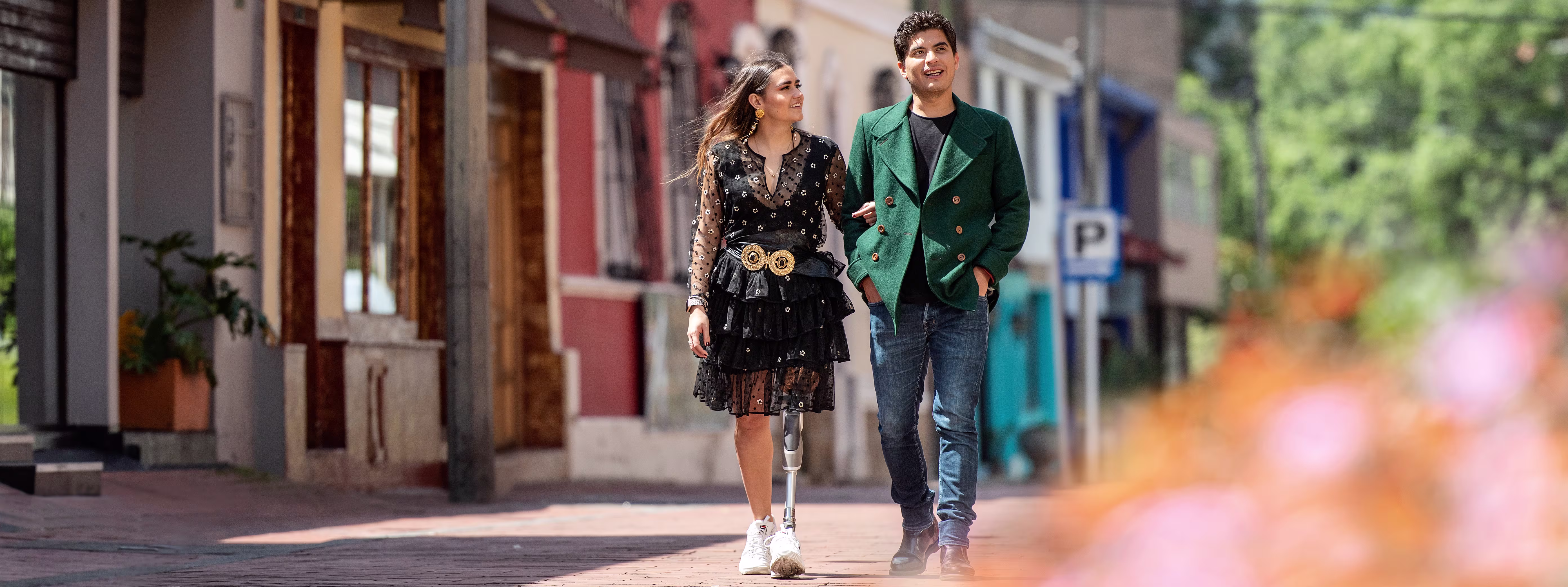 Microprocessor knee user walks along a brick road with a friend