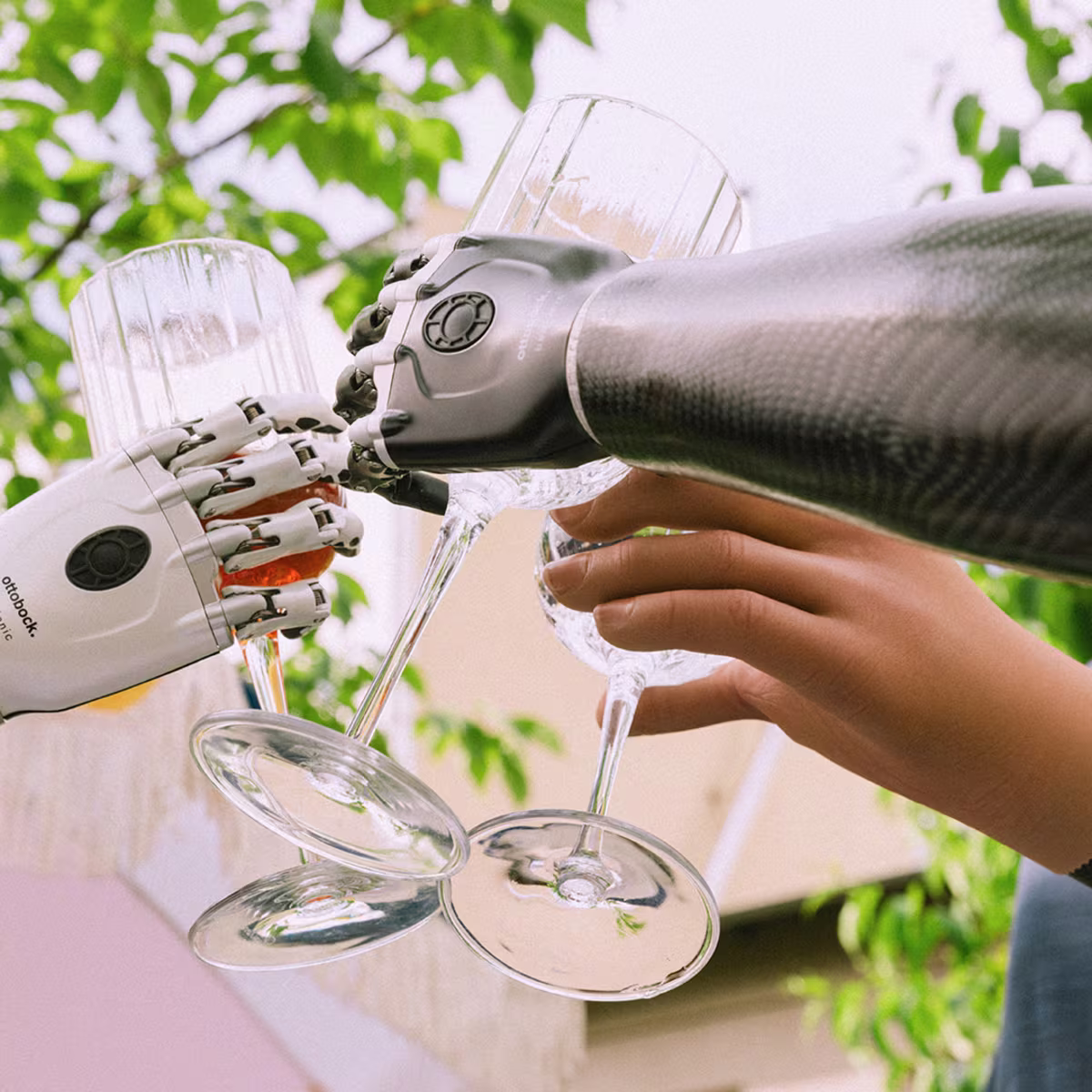 Drei Armprothesenträger halten Gläser mit Hilfe ihrer Handprothesen und stoßen damit an.