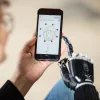 A female individual uses her smartphone to activate the Myo Plus app and optimize the movements of her bebionic hand
