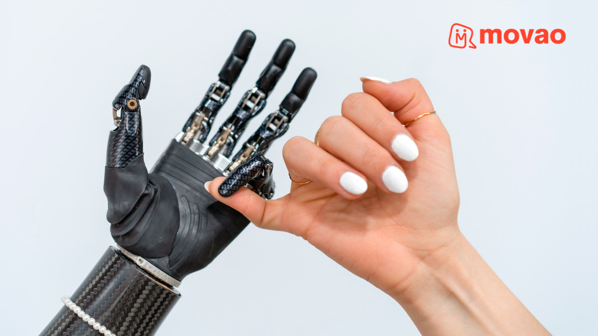 Gruppo di persone che sollevano insieme i loro arti e mani protesici Ottobock, simbolo di sostegno e comunità – logo Movao visibile.