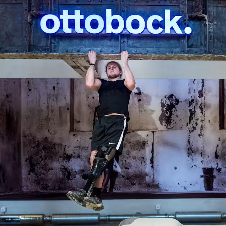 A microprocessor knee ankle foot orthosis user doing pull ups in an industrial-style room while wearing the C-Brace by Ottobock
