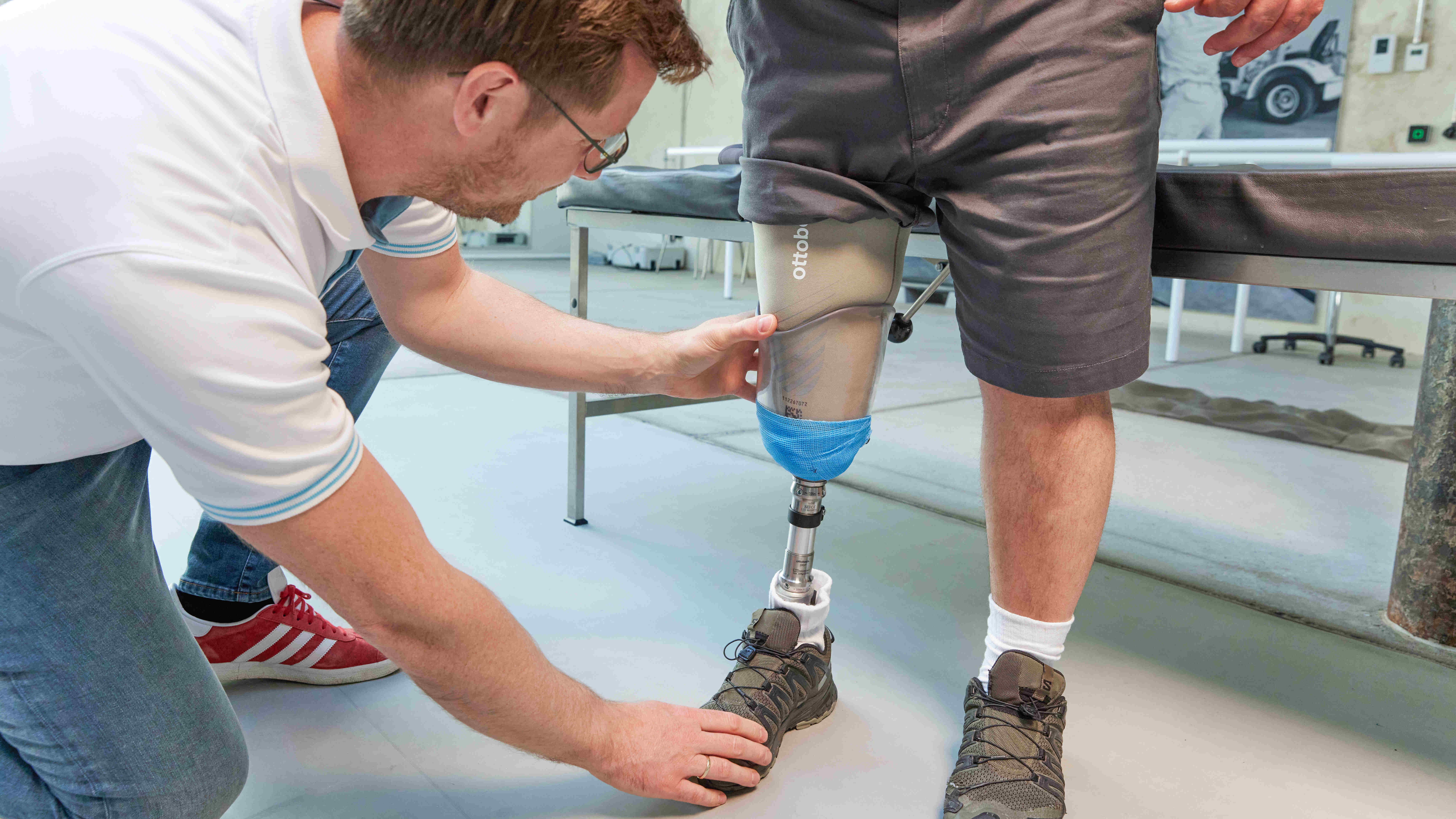 A below knee amputee has his prosthetic socket fitted by a prosthetist.