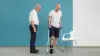 Un hombre con un talón fracturado usa muletas y una ortesis de alivio del talón mientras un especialista le enseña a caminar con ambos dispositivos