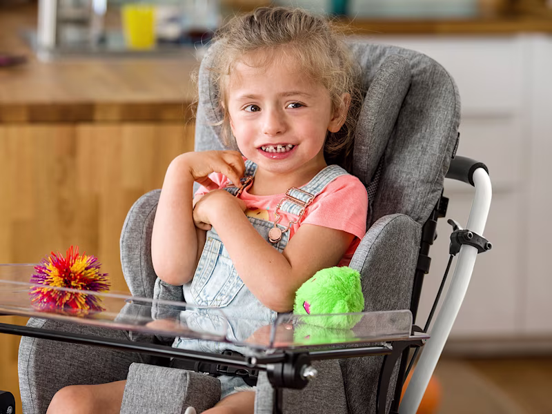 Emilia, ein kleines Mädchen, sitzt in ihrem Kimba Home und lächelt in die Kamera.