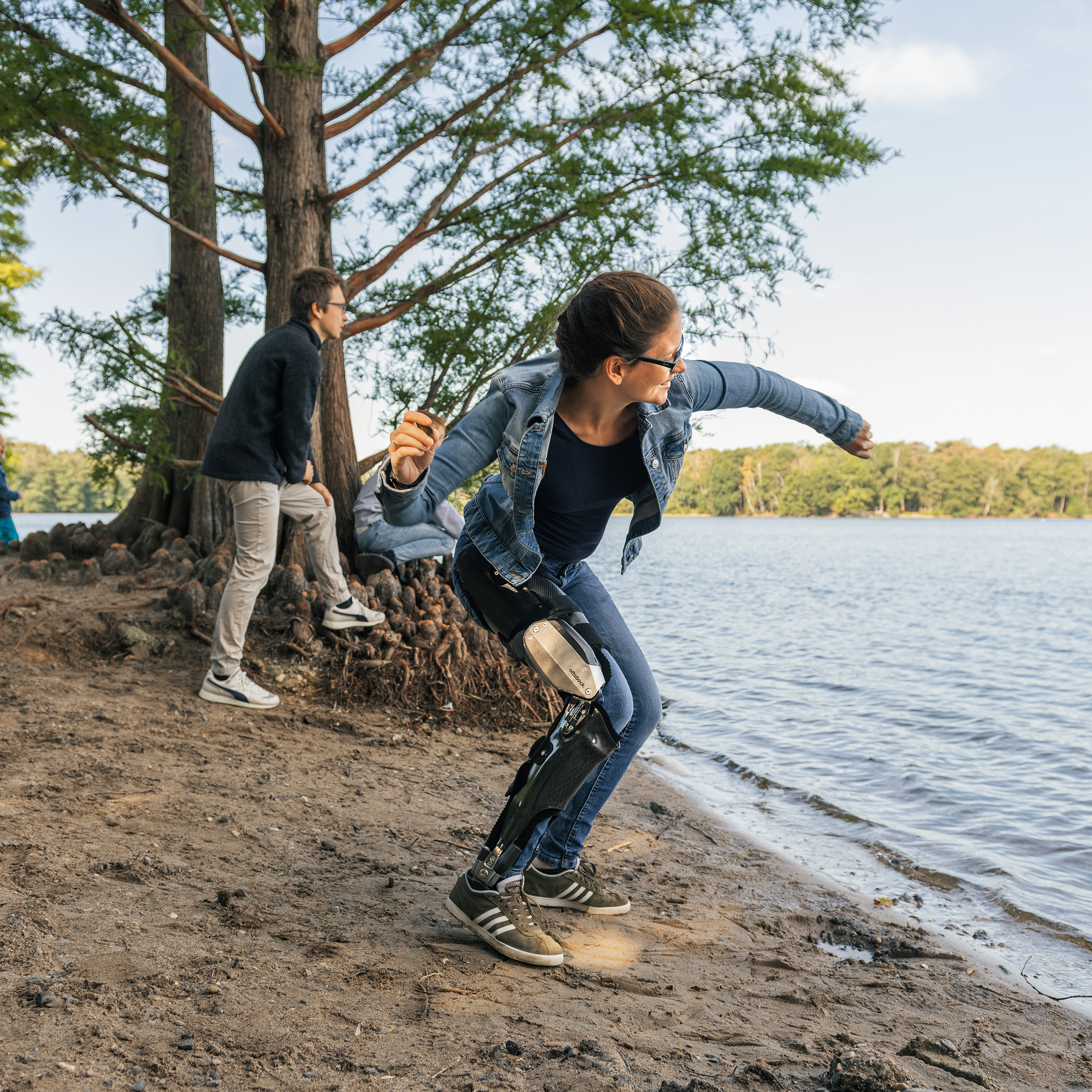 Lady wearing C-brace throwing a stone in the river.