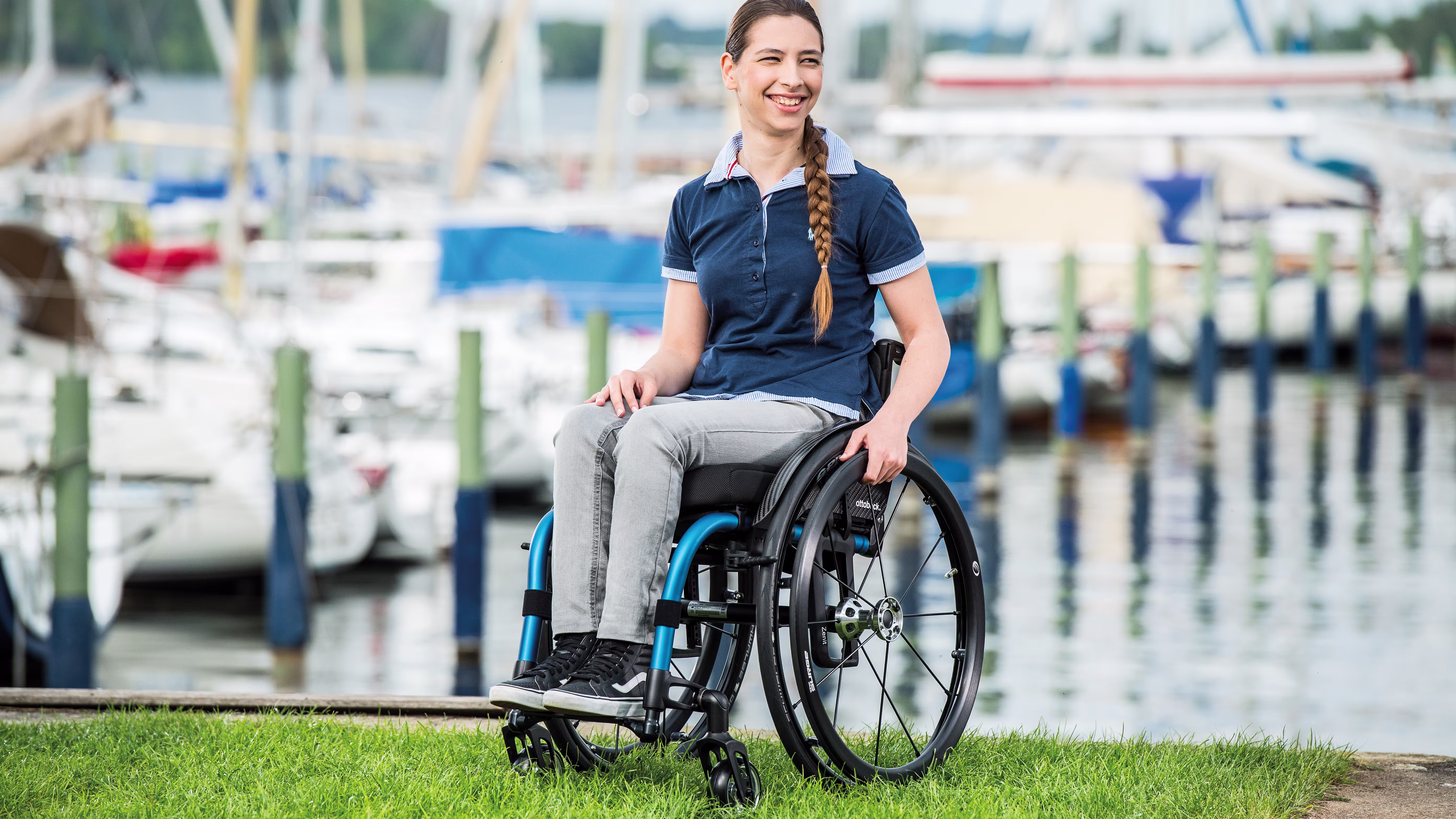 A young woman sitting in her Zenit R manual wheelchair from Ottobock in front of a harbour 