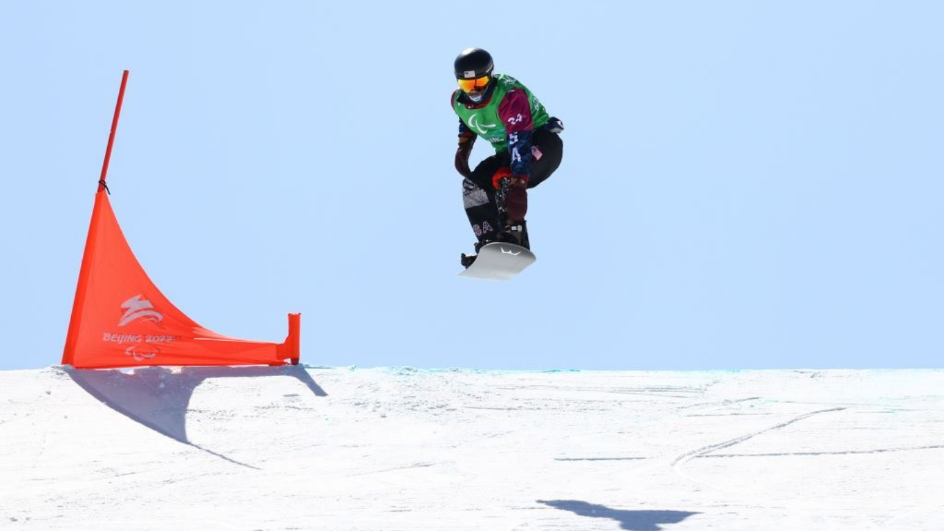 Adaptive snowboarder in the air after having just taken a jump during a racing event