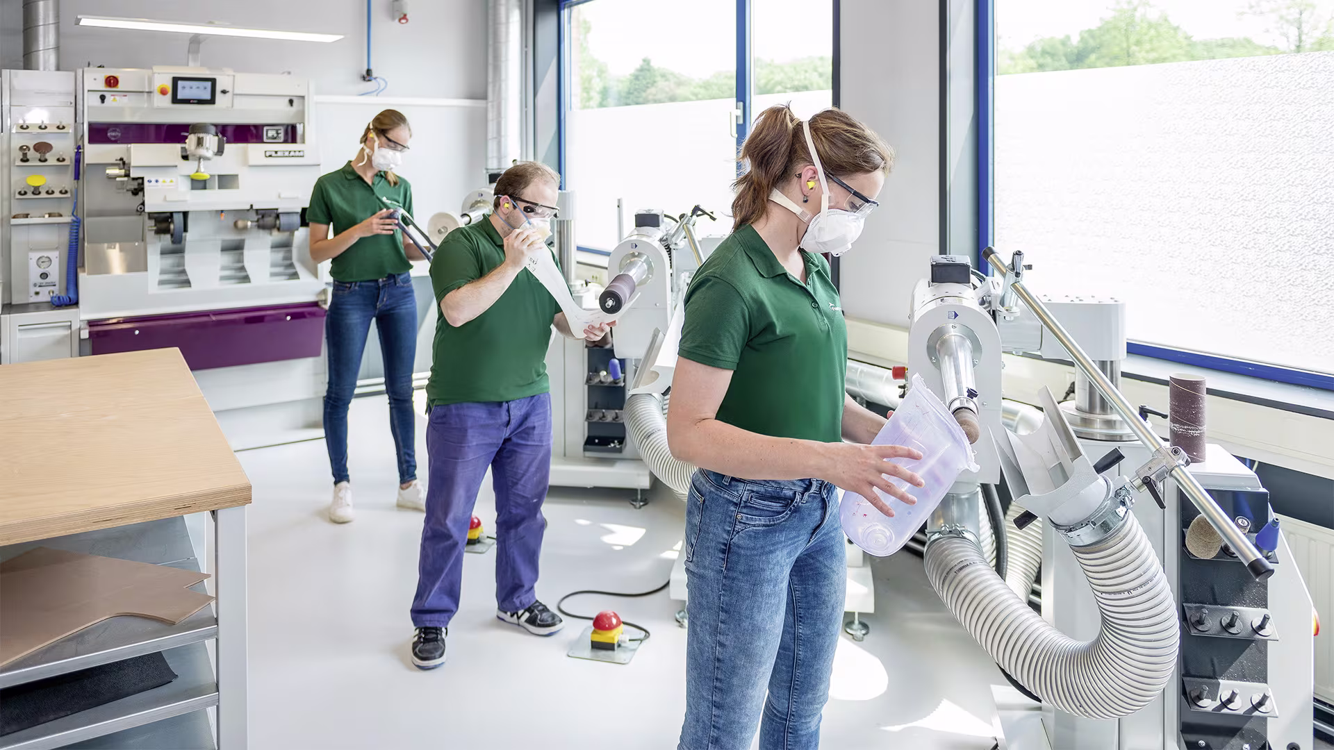 Team of technicians in protective gear working with manufacturing equipment in Ottobock lab.