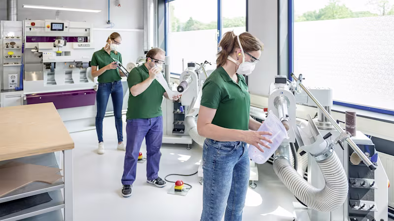 Team of technicians in protective gear working with manufacturing equipment in Ottobock lab.