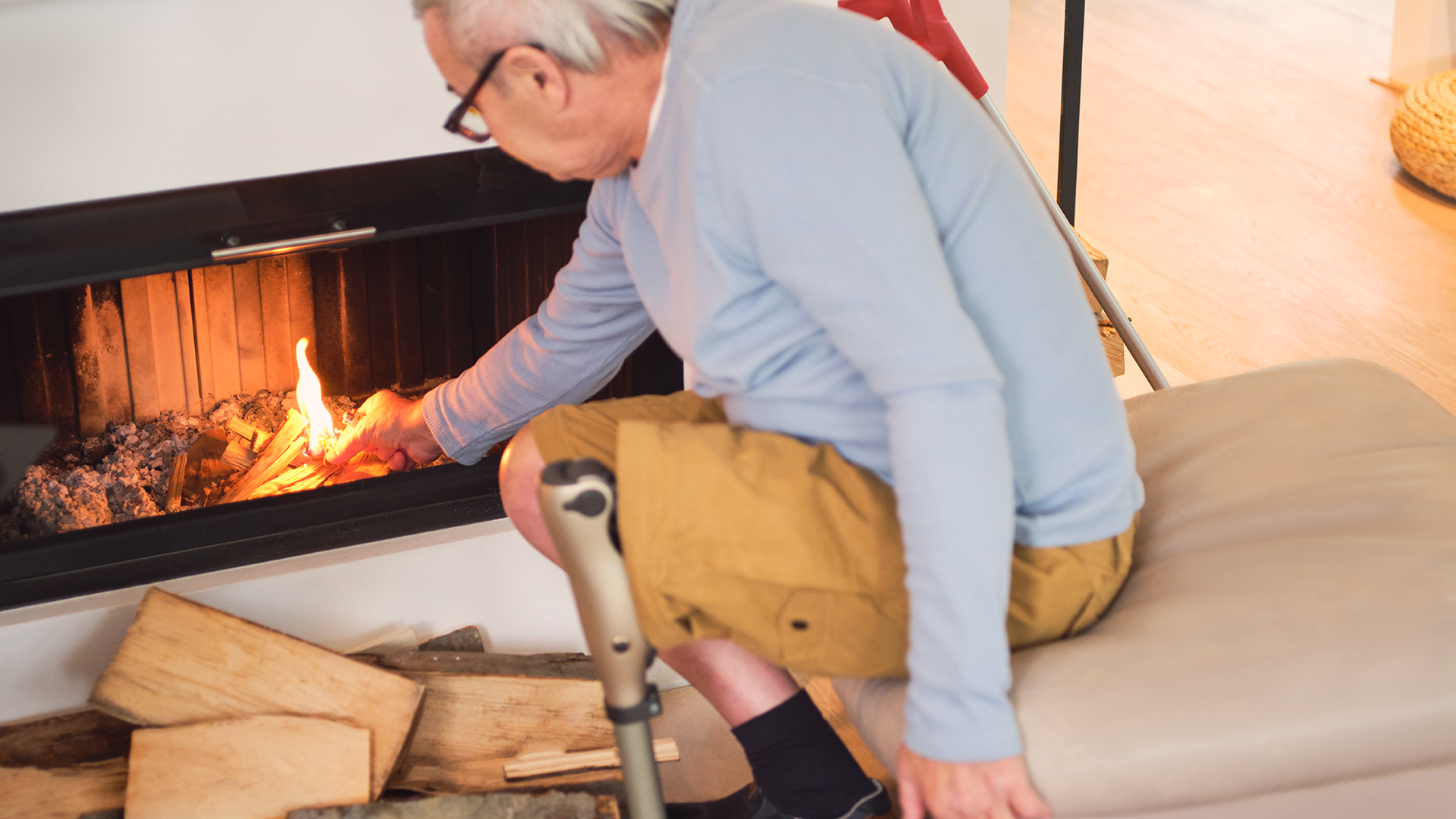 Un aîné portant une prothèse au genou ajoute du feu à son foyer .