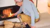 An elder wearing a prosthetic knee adds kindle to his fire place