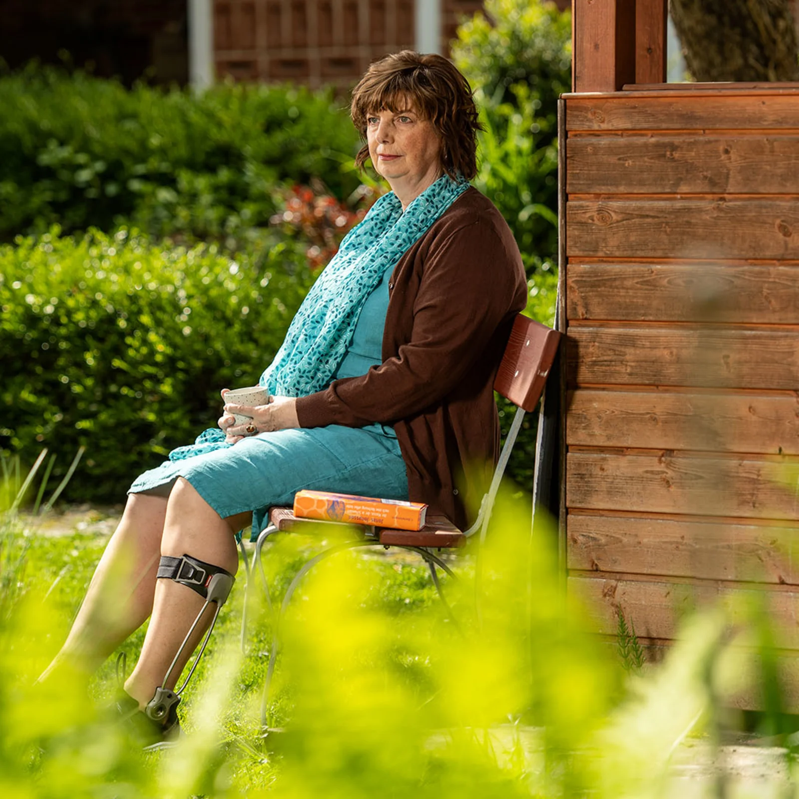 Silvia sitzt auf einer Bank im Grünen, Sie trägt dabei an ihrem linken Bein die Agilium Freestep 3.0