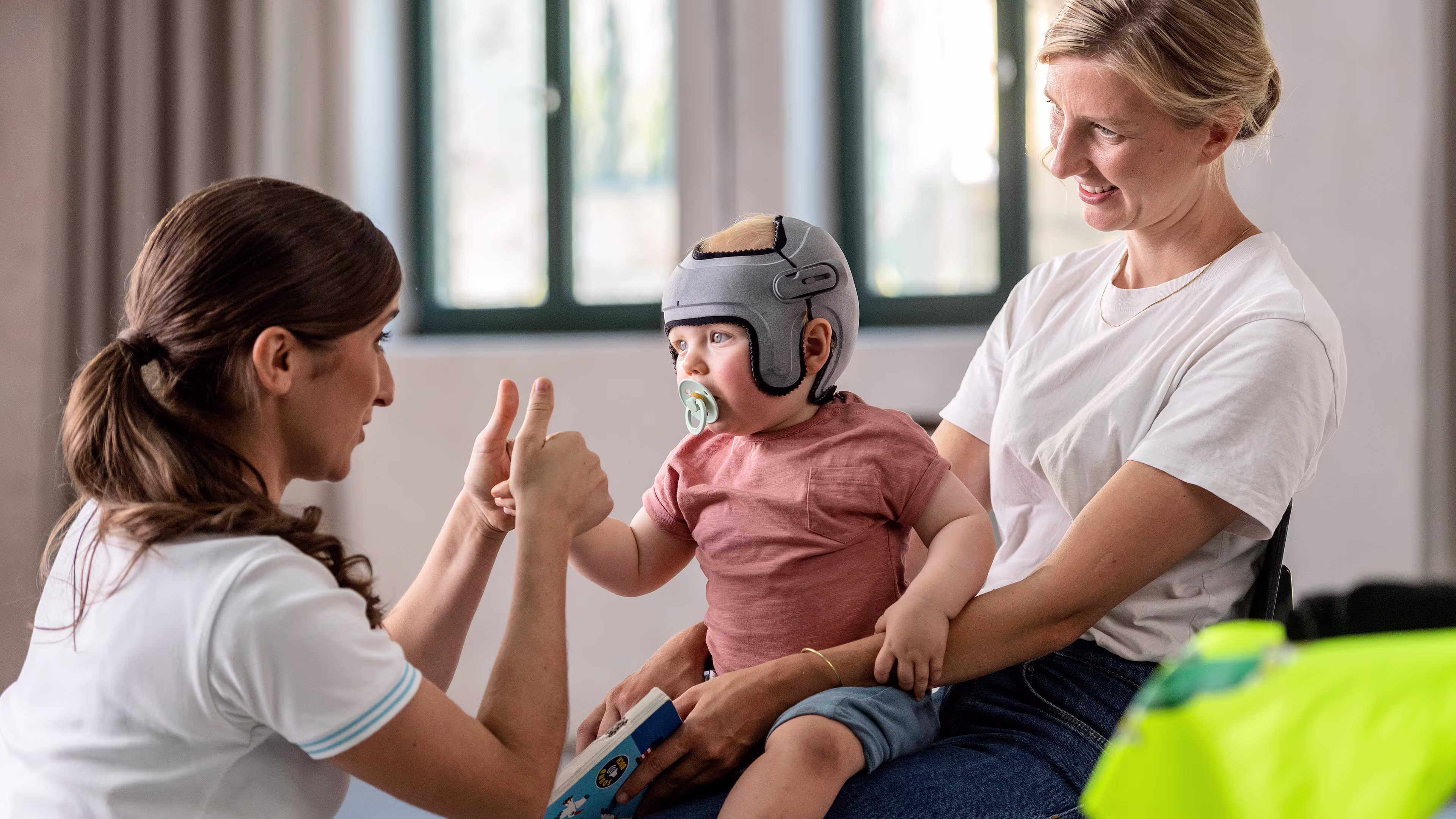 Baby on mother’s lap at a doctor’s visit wearing Ottobock MyCRO Band cranial remolding orthosis. 