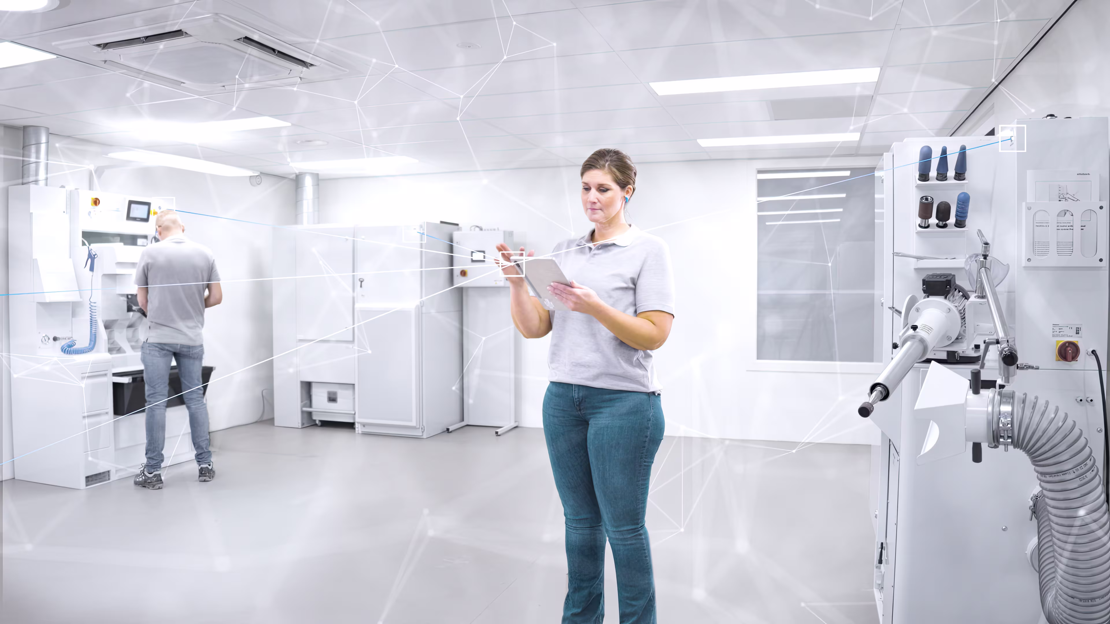 Eine Mitarbeiterin hält ein Tablet , um sich über Ottobock work.hub mit den Maschinen zu verbinden, dabei steht Sie in einer Orthopädiewerkstatt.