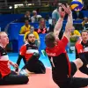 A team of amputated volleyball players watch intently as their teammate reaches for the ball