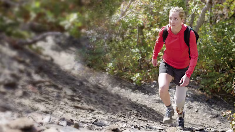 Eine Frau in Wanderoutfit erklimmt einen steilen Bergweg.