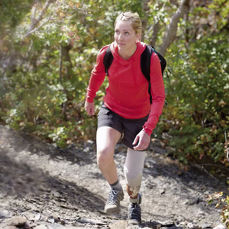 Eine Frau in Wanderoutfit erklimmt einen steilen Bergweg.