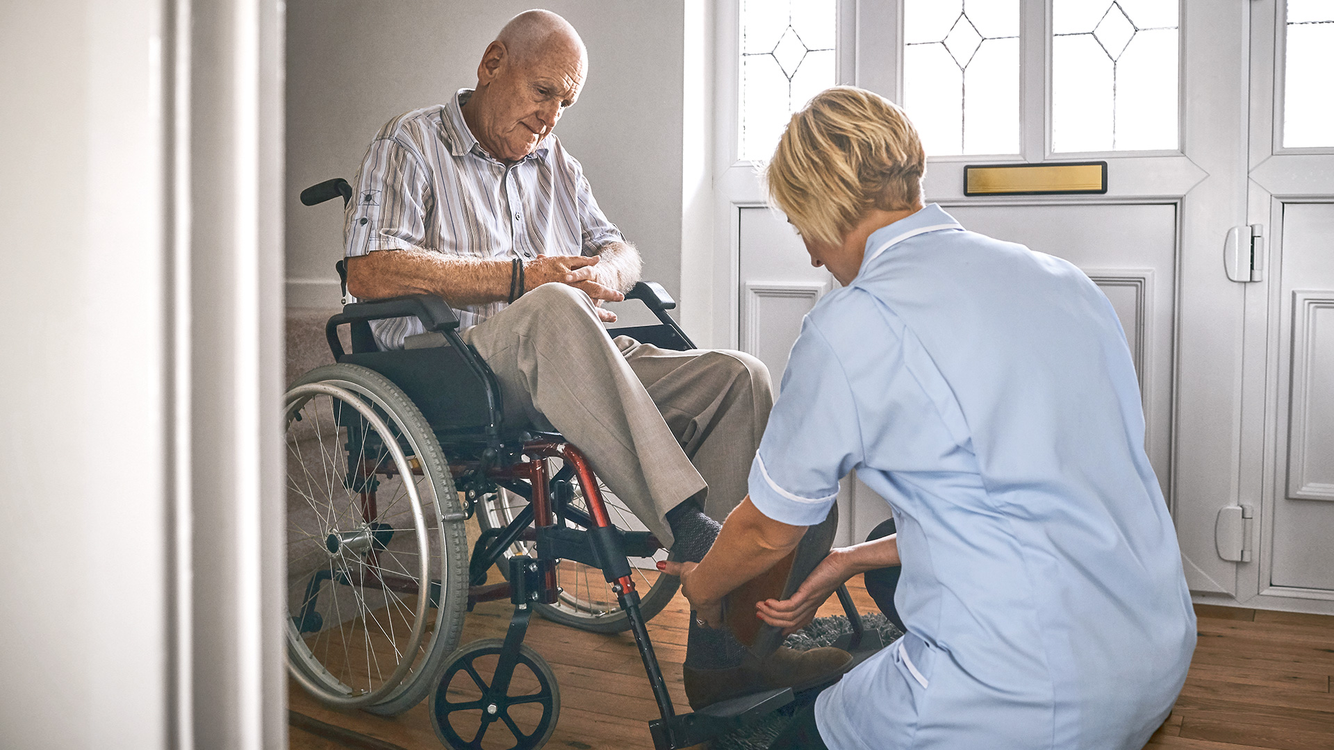 A woman helps a man in a wheelchair to position his foot.