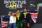 Three veteran athletes at the Invictus Games pose with their medals and national flags.