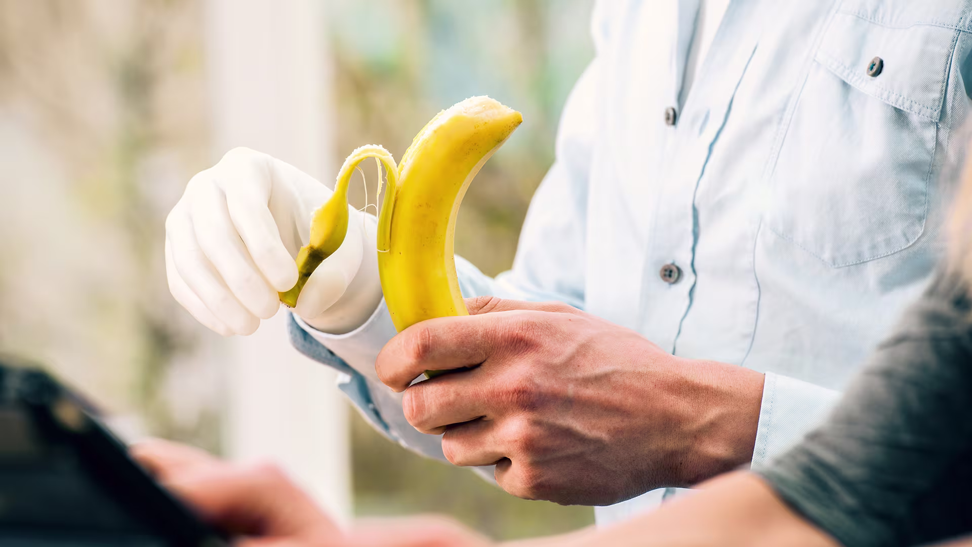 Persona que muestra una prótesis de mano mientras pela un plátano durante una demostración práctica del producto.