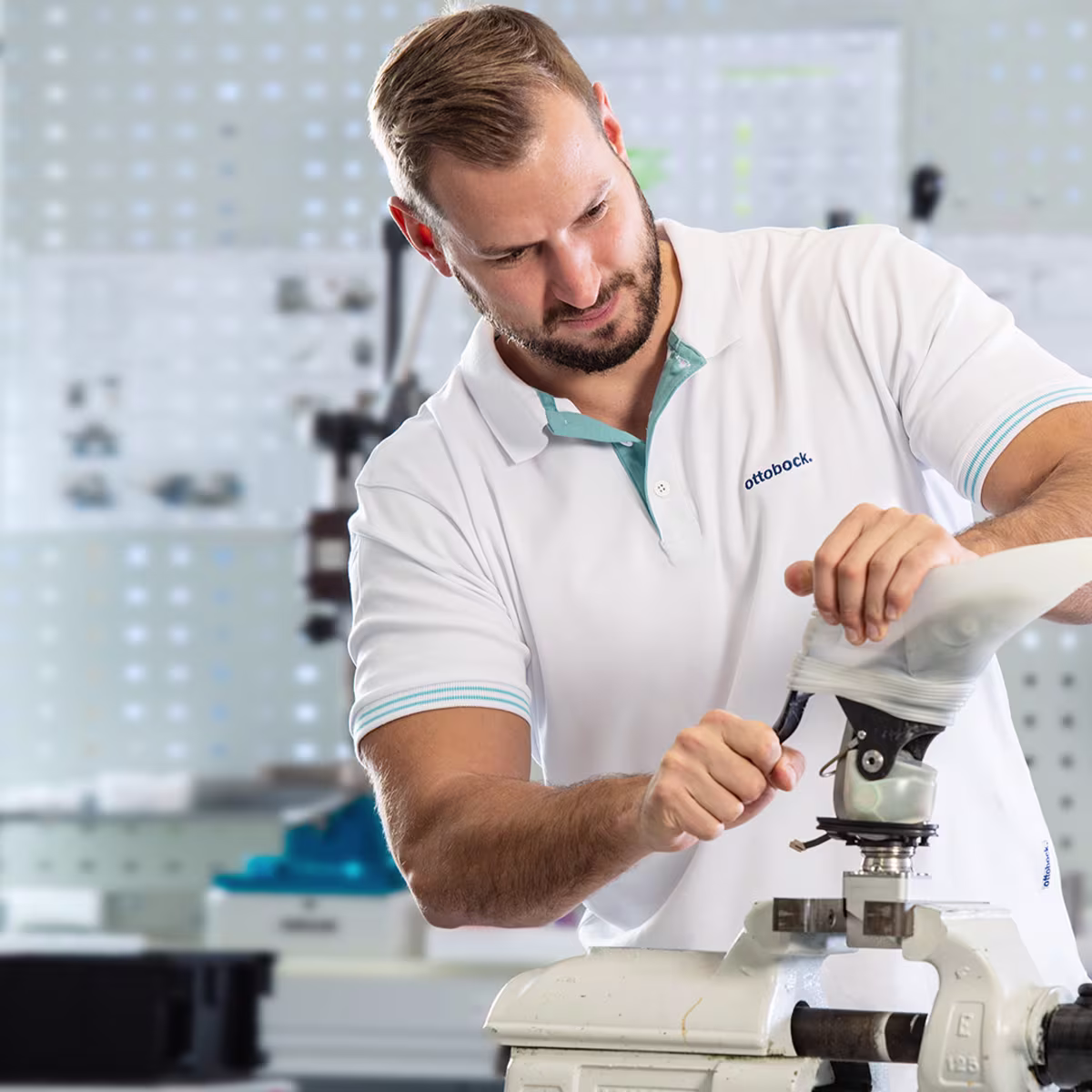 Ottobock technician assembling prosthetic limb in specialized workshop environment.