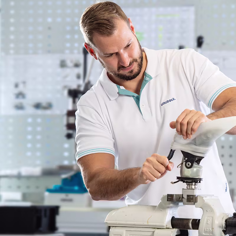 Ottobock technician assembling prosthetic limb in specialized workshop environment.