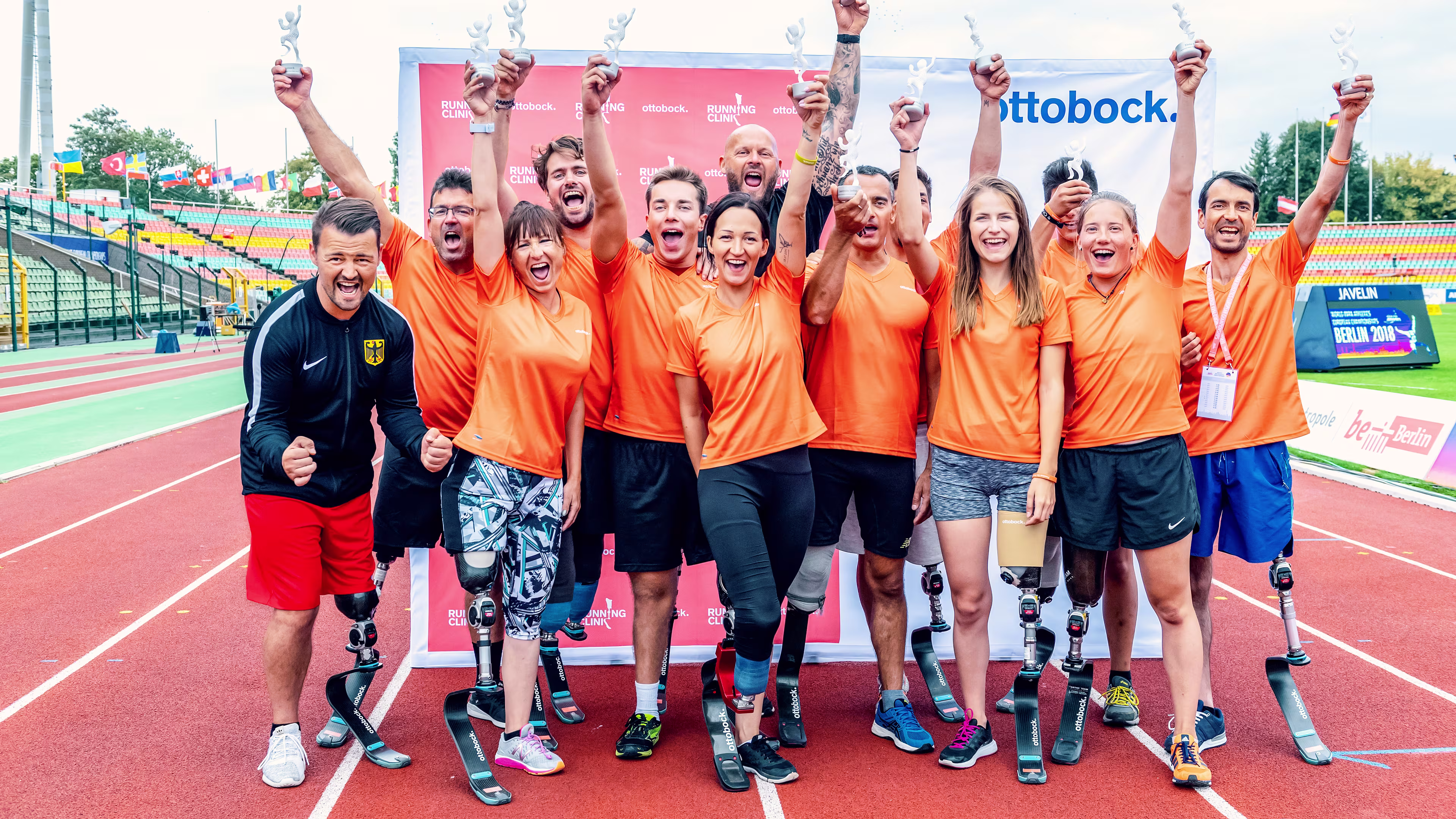 Teilnehmer der Running Clinic stehen gemeinsam auf dem Sportplatz und jubeln.