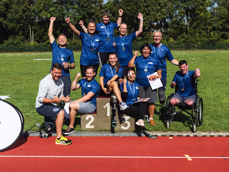 Teilnehmer der Running Clinic stehen gemeinsam auf dem Sportplatz und jubeln