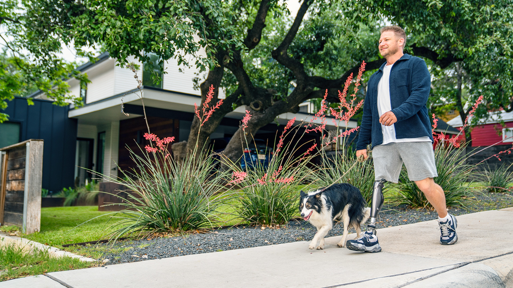 C-Leg user Chance is walking his dog on a sidewalk.