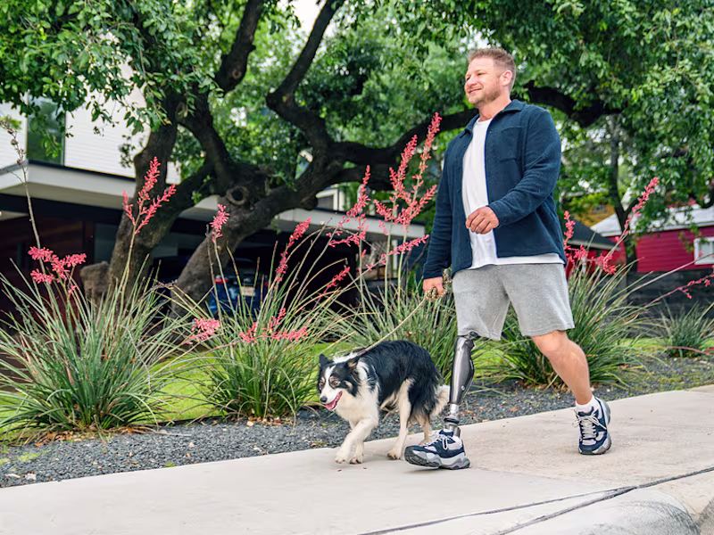 C-Leg user Chance is walking his dog on a sidewalk.