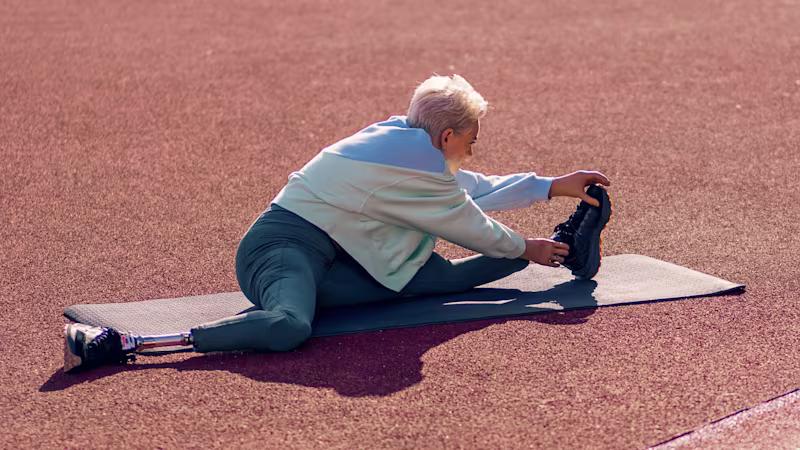 Ottobock biyonik el kullanıcısı Bebe, koşu parkurunda yoga matı üzerinde sol bacağını esnetiyor