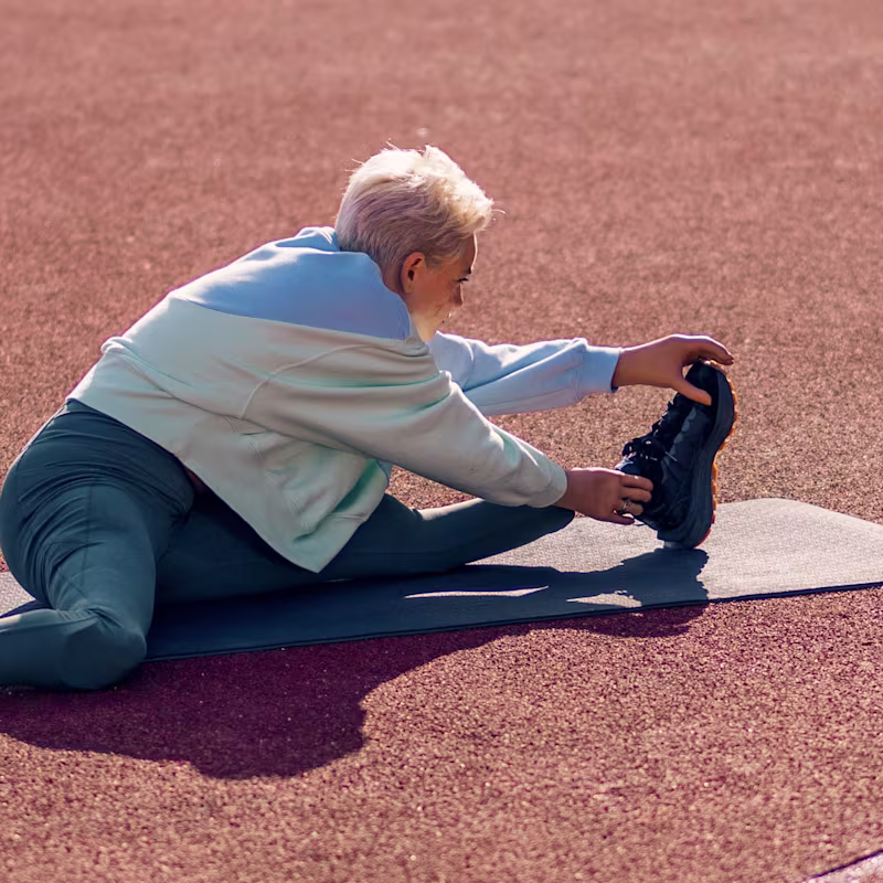Ottobock biyonik el kullanıcısı Bebe, koşu parkurunda yoga matı üzerinde sol bacağını esnetiyor