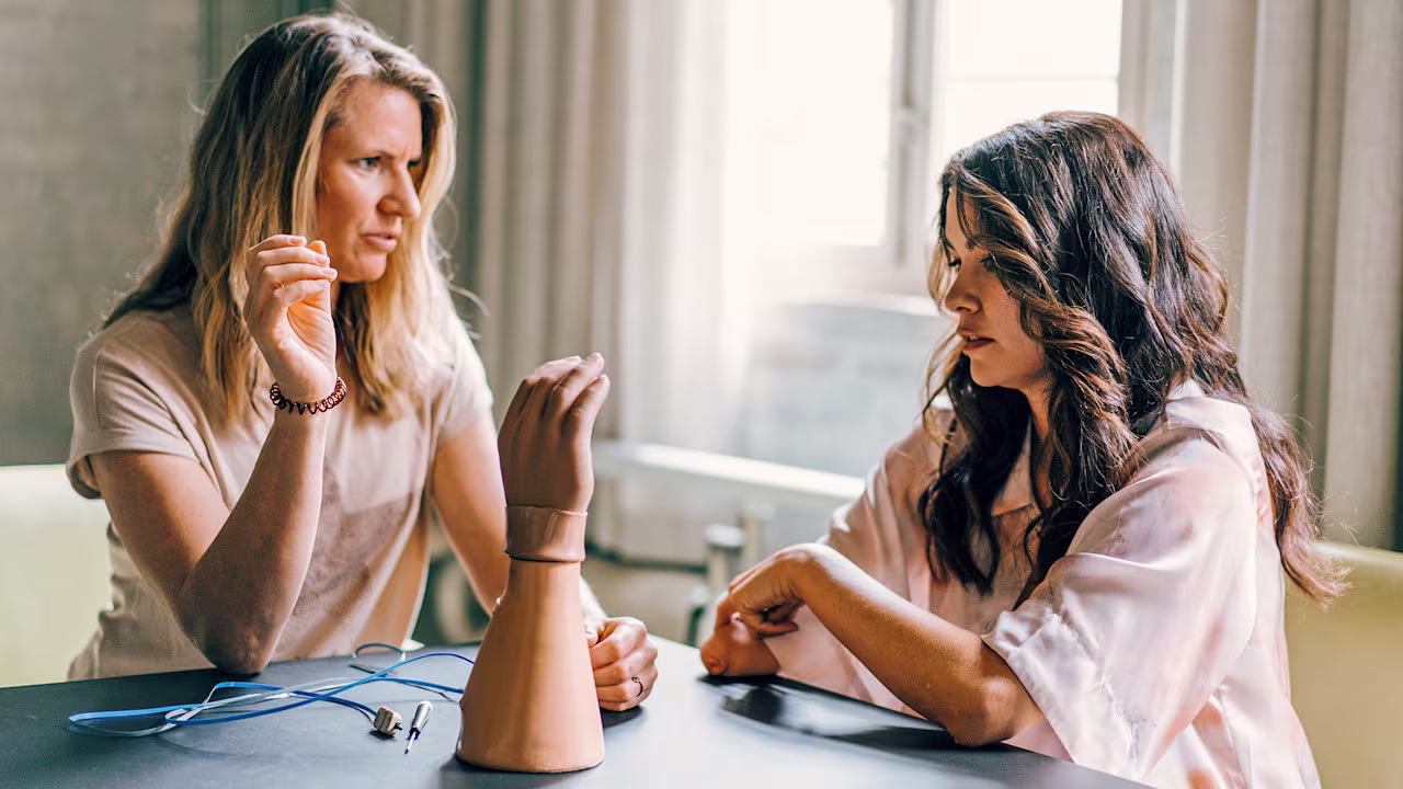 Two prosthetic arm users having a conversation at a table