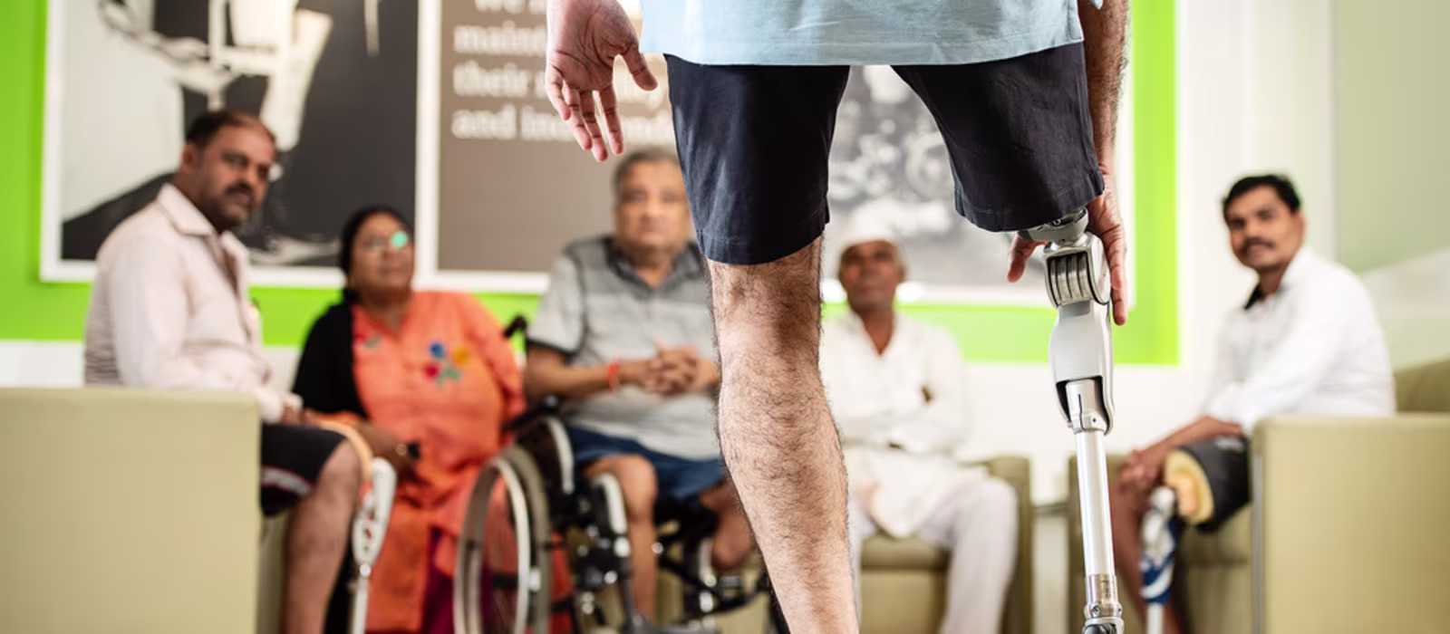 An amputee with a prosthetic leg faces a group of prosthetic users