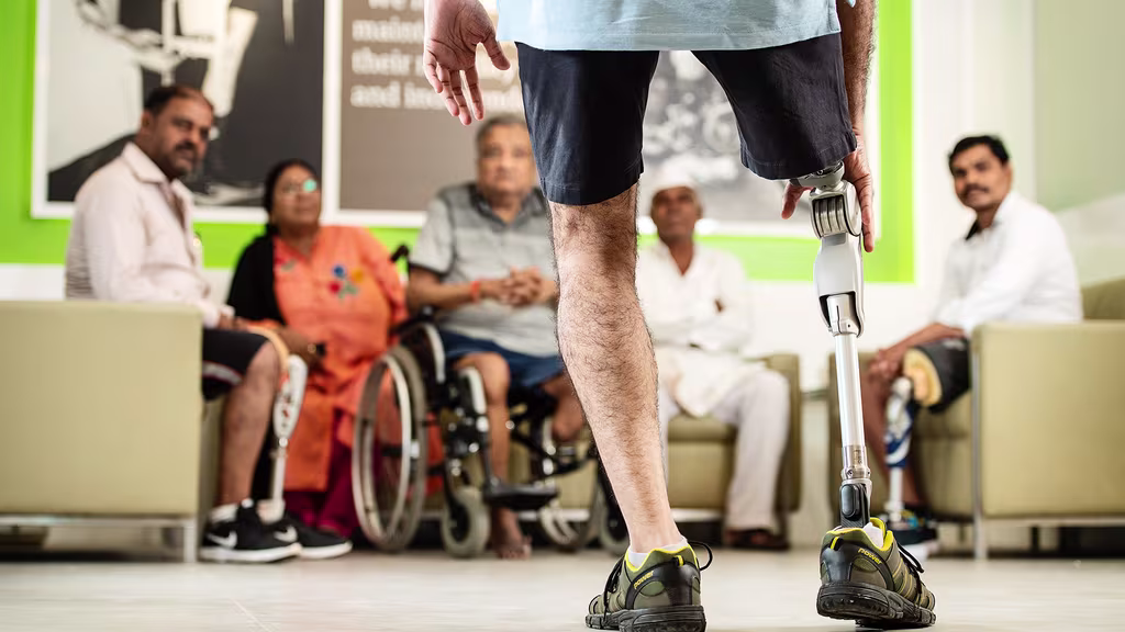 An amputee with a prosthetic leg faces a group of prosthetic users