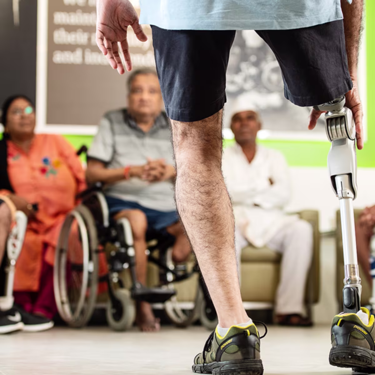 An amputee with a prosthetic leg faces a group of prosthetic users