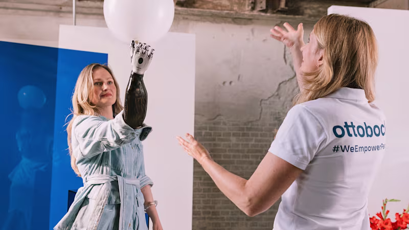 A bebionic user holding a white balloon with their prosthetic hand during a session with their physiotherapist