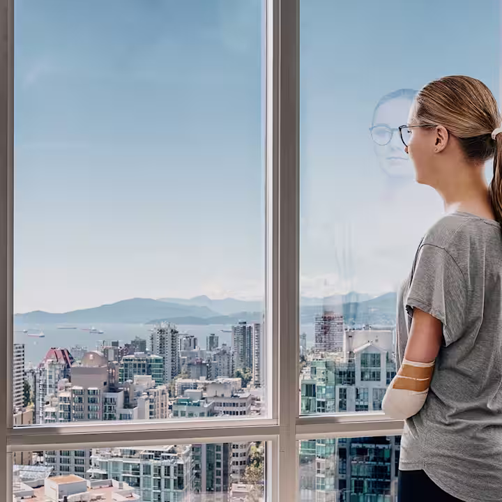 Eine Anwenderin steht am Fenster und guckt raus