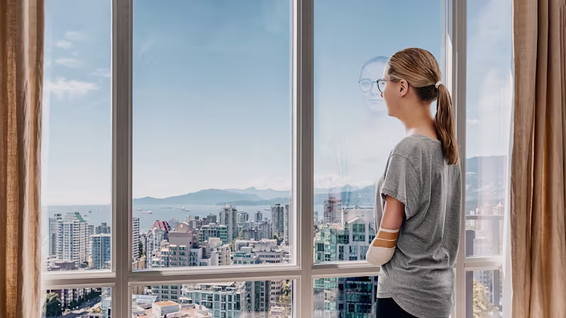 Eine Anwenderin steht am Fenster und guckt raus